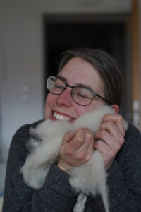 Mona kuschelt das Gesicht in Spinnwolle
