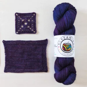 handgefärbte Wolle in Lila-Tönen mit einer gehäkelten und einer gestrickten Maschenprobe